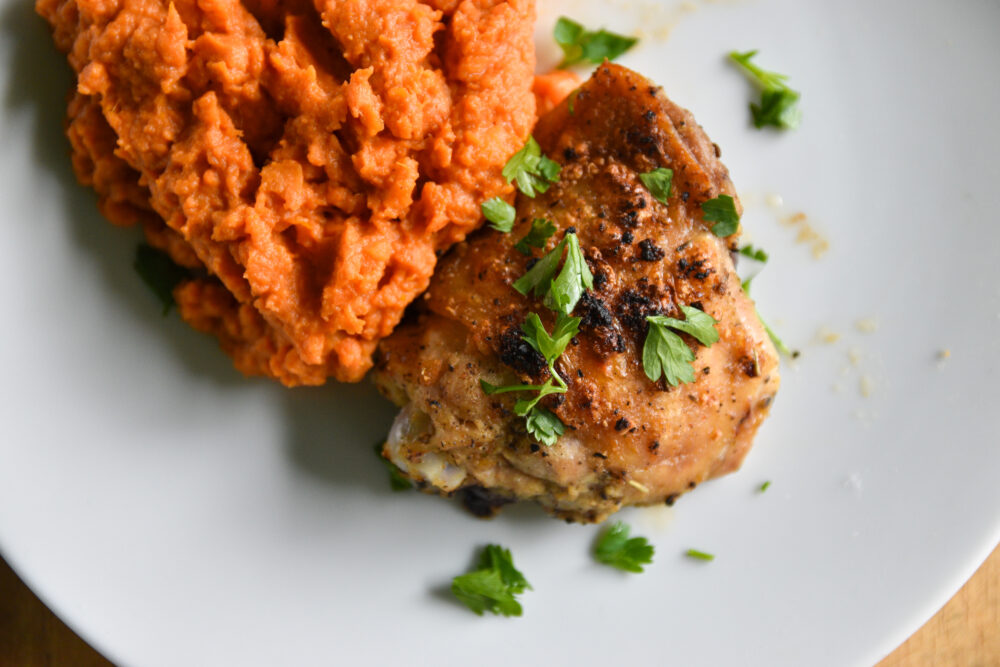 Oven-roasted chicken and sweet potato mash, plated on a white dish