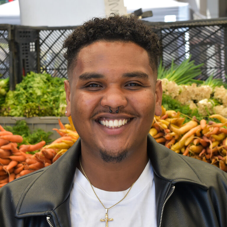 Headshot of Marcelo Clark, with carrots in the background